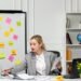 Marketing young cute blonde girl in grey suit in the office writing something in notepad.