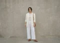 Woman wearing a layered all-white outfit with an ivory blazer and cream knit in daylight