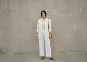 Woman wearing a layered all-white outfit with an ivory blazer and cream knit in daylight