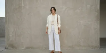 Woman wearing a layered all-white outfit with an ivory blazer and cream knit in daylight