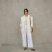 Woman wearing a layered all-white outfit with an ivory blazer and cream knit in daylight