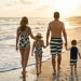 Family of four in coordinated navy and cream swimwear walking along a beach