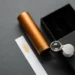 Aluminum perfume bottle, open box and jeweler’s loupe arranged for an authenticity inspection