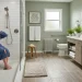 A modern, accessible bathroom featuring a curbless walk-in shower with a built-in bench, grab bars, non-slip flooring, and a floating wooden vanity.