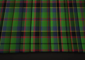 Close-up of dark green and navy tartan fabric, crossed by fine red and yellow lines in a repeating plaid pattern with subtle folds and a traditional feel.